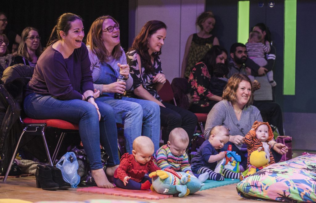 mothers and babies laughing at a comedian