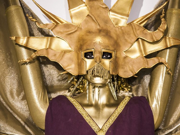 A golden clad dummy wearing a golden sun mask