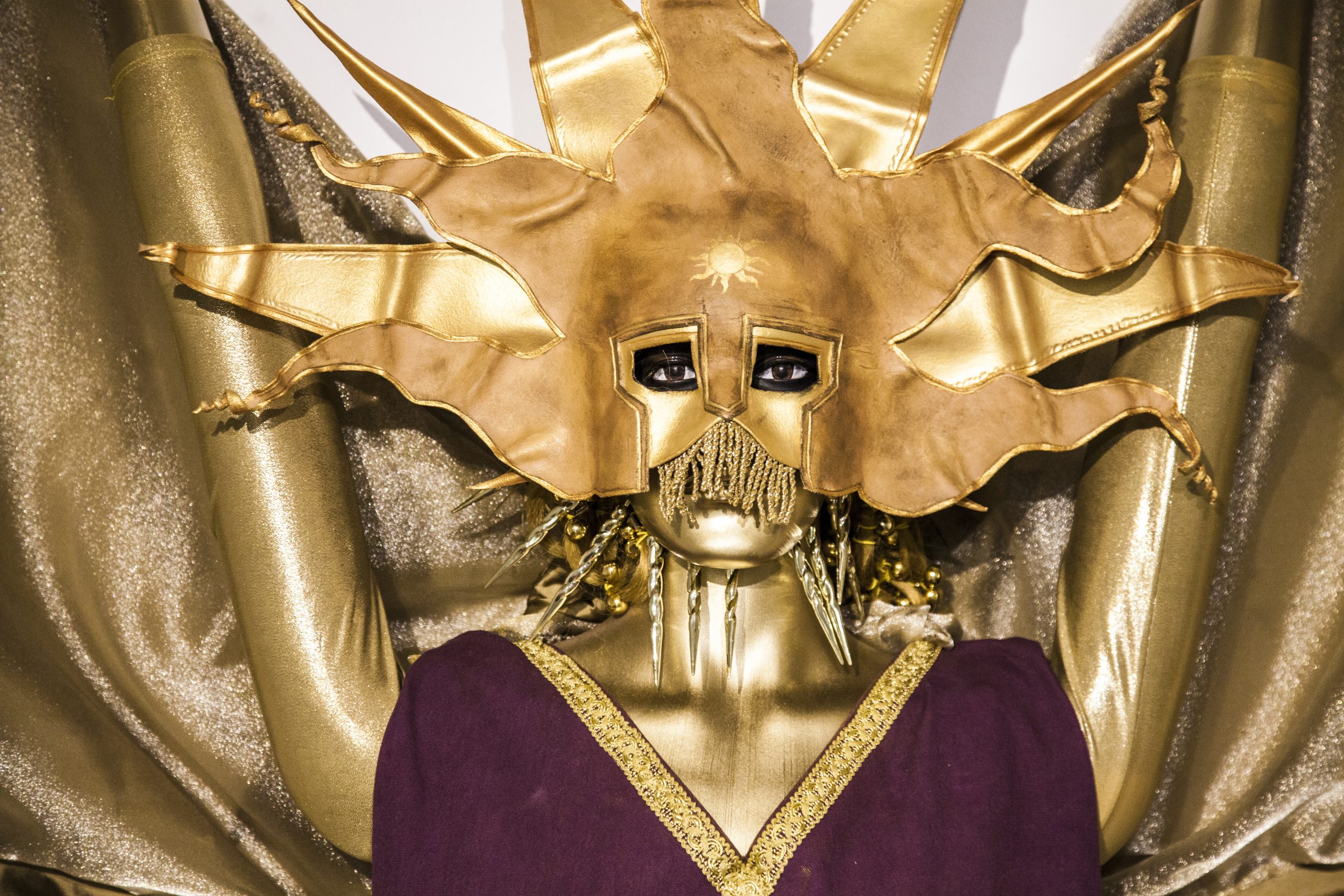 A golden clad dummy wearing a golden sun mask