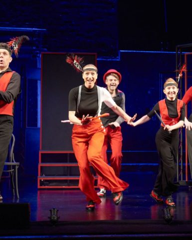 5 people in black and red dancing on stage