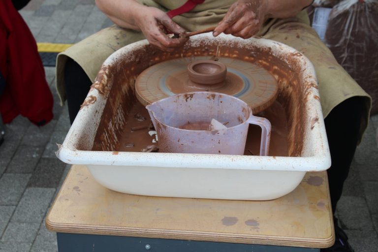 Hands turning clay on a wheel.