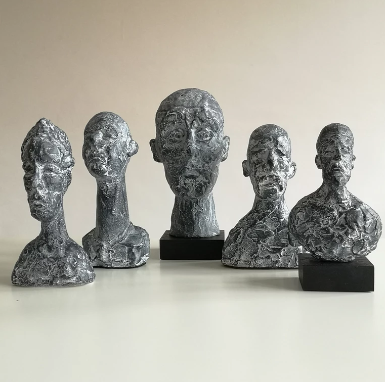 Five ceramic heads sit against a cream background.