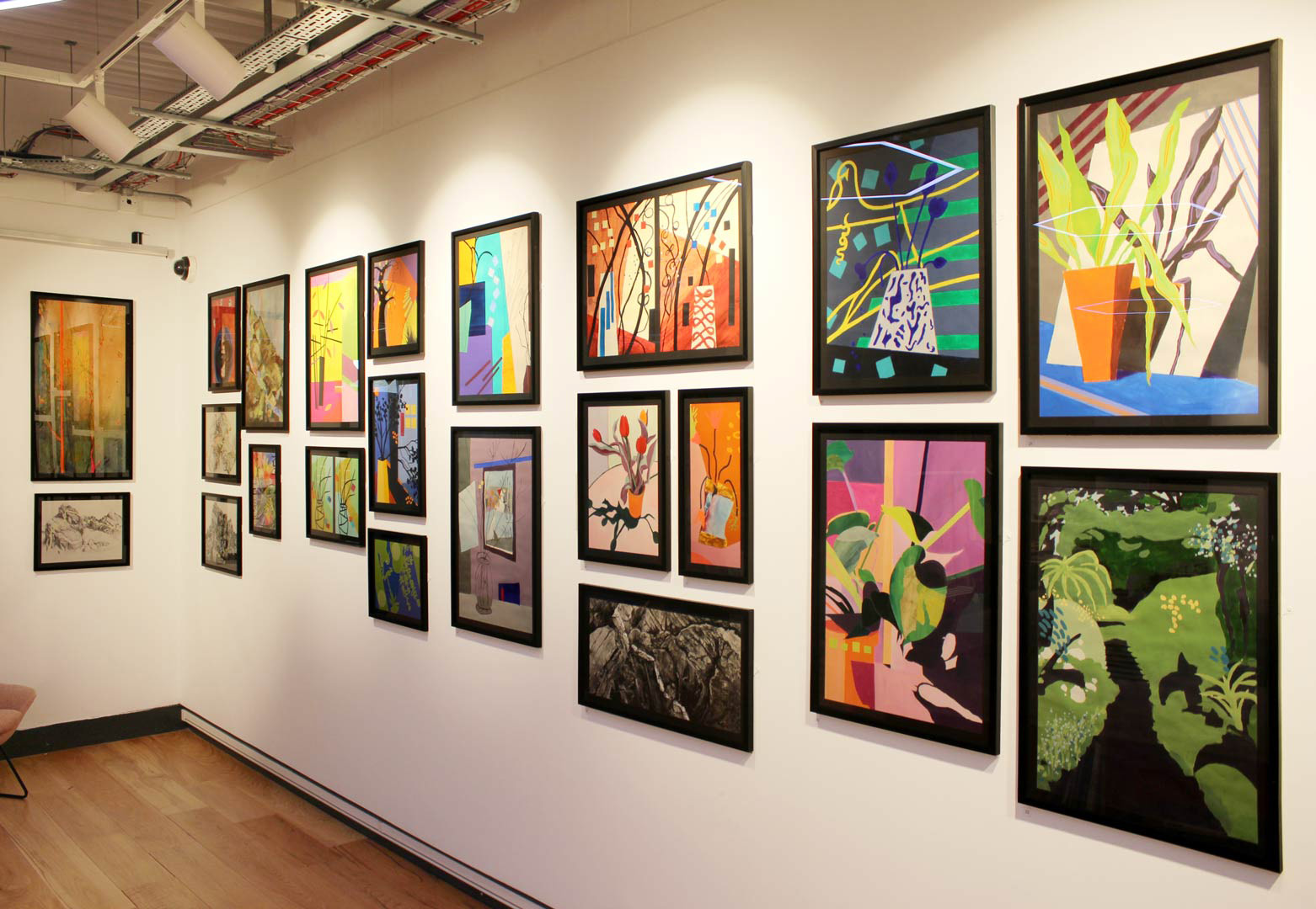 A corner of the Salmon Gallery, with the walls covered in brightly coloured framed artworks.