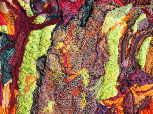 A mixture of coloured textiles, red, browns and neon greens sewn together to create a textile painting