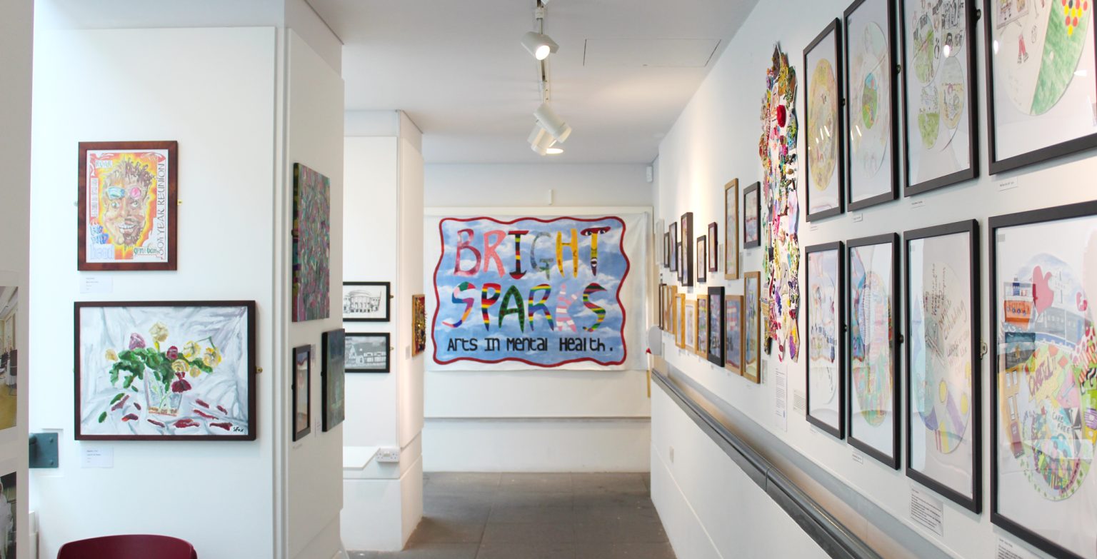 The Balcony Gallery with the walls covered in art and the Bright Sparks flag on the wall at the far end.