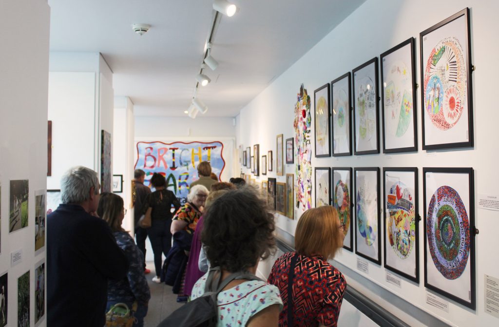 The Balcony Gallery with a lot of art on the walls, full to the brim with visitors.