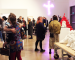 An array of people in Gallery 1 hugging and talking, surrounded by neon lights and marble carvings by Tony Heaton.