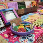 A table full of colourful, handmade crafts including buttons, frames and greeting cards.