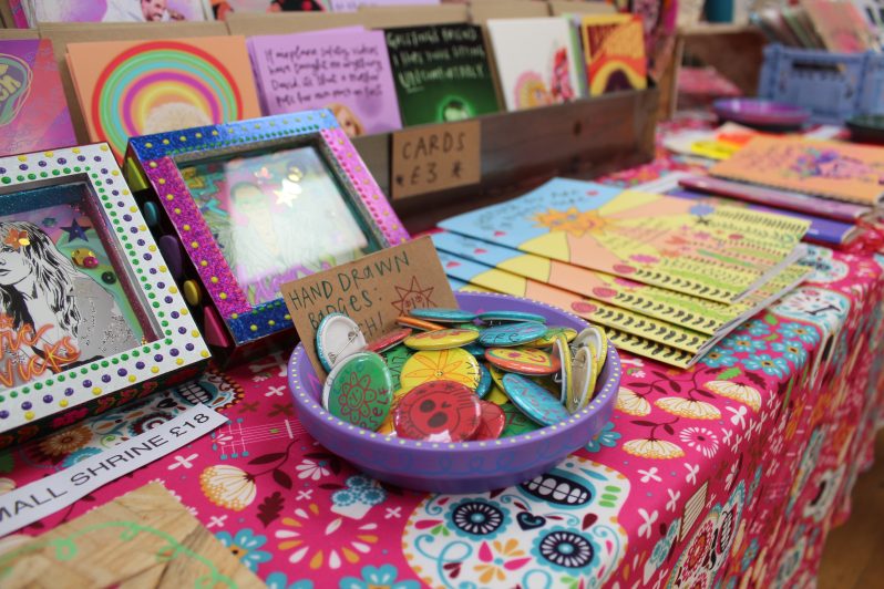 A table full of colourful, handmade crafts including buttons, frames and greeting cards.