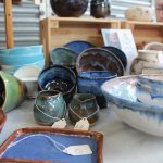 A table full of handmade ceramics in blues, greens, white and brown glazes.