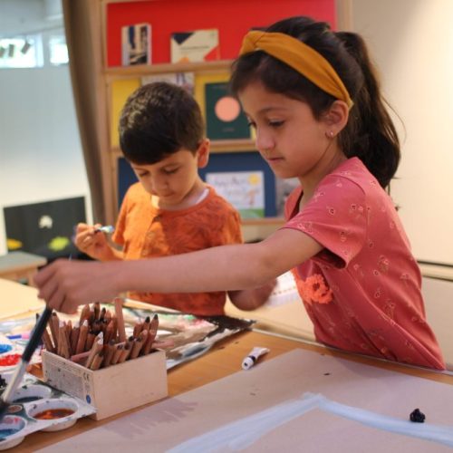 Two children using paint brushes to pick up paints.