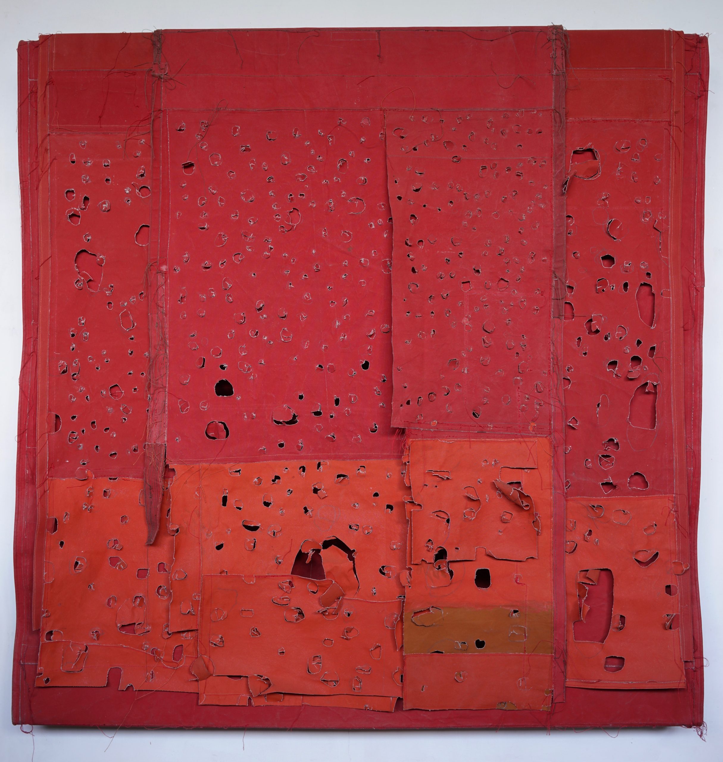 A canvas covered in ripped and damaged patches of various shades of red.