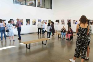 A group of people in a large gallery space looking at portraits on the wall.