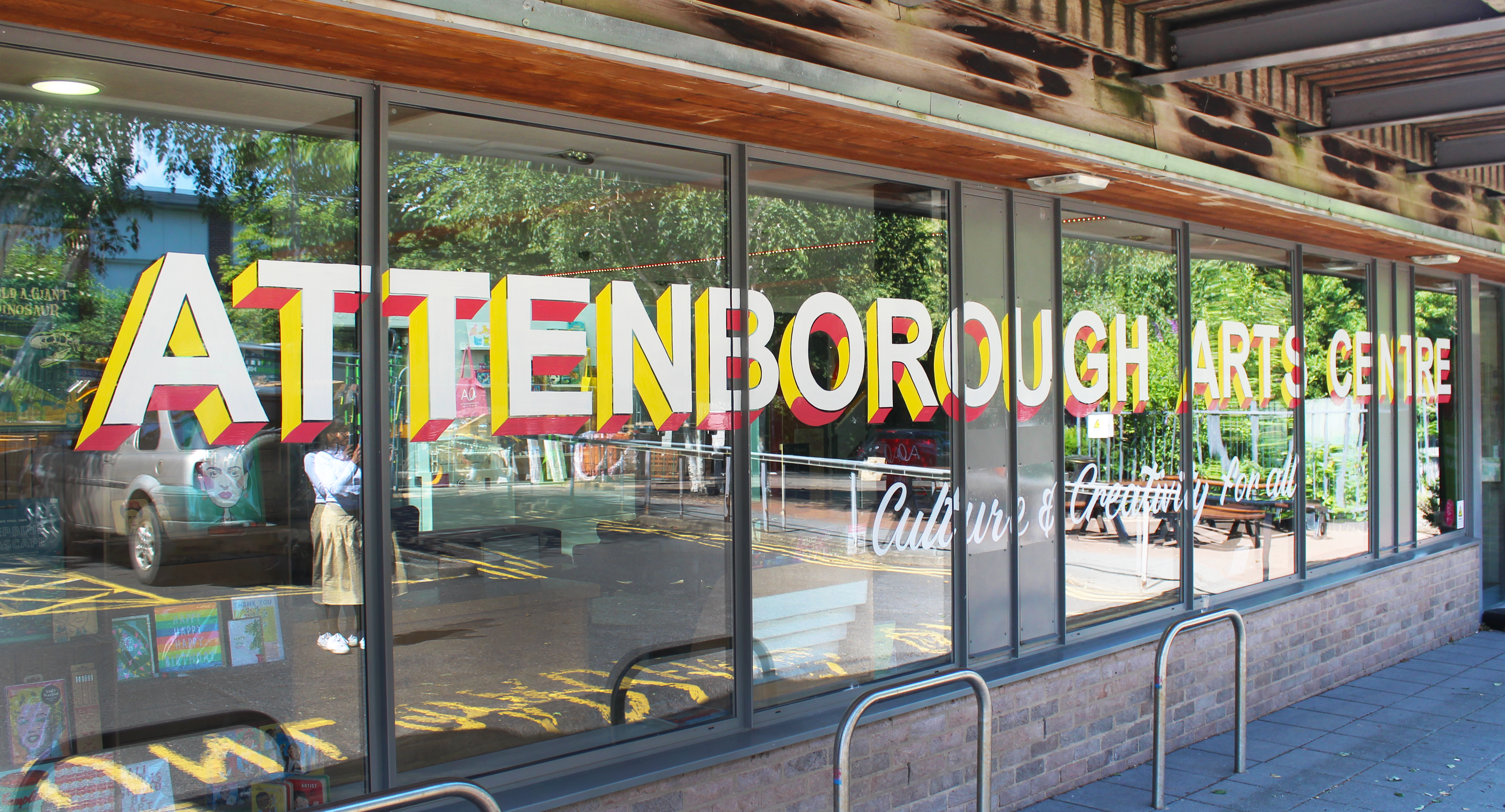 The front windows of Attenborough Arts Centre with sign writing saying 'Attenborough Arts Centre, Culture & Creativity for all'.