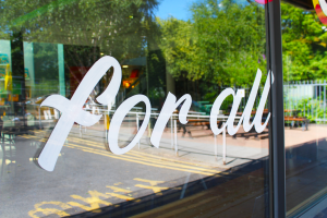 A reflective window with the script 'for all' sign written across the surface.