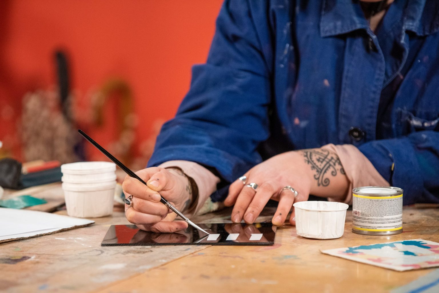 A hand painting onto a mirror with a brush.