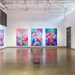 A large white gallery with huge colourful botanical paintings covering the walls.