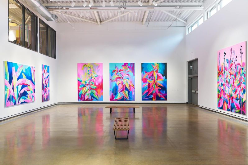 A large white gallery with huge colourful botanical paintings covering the walls.