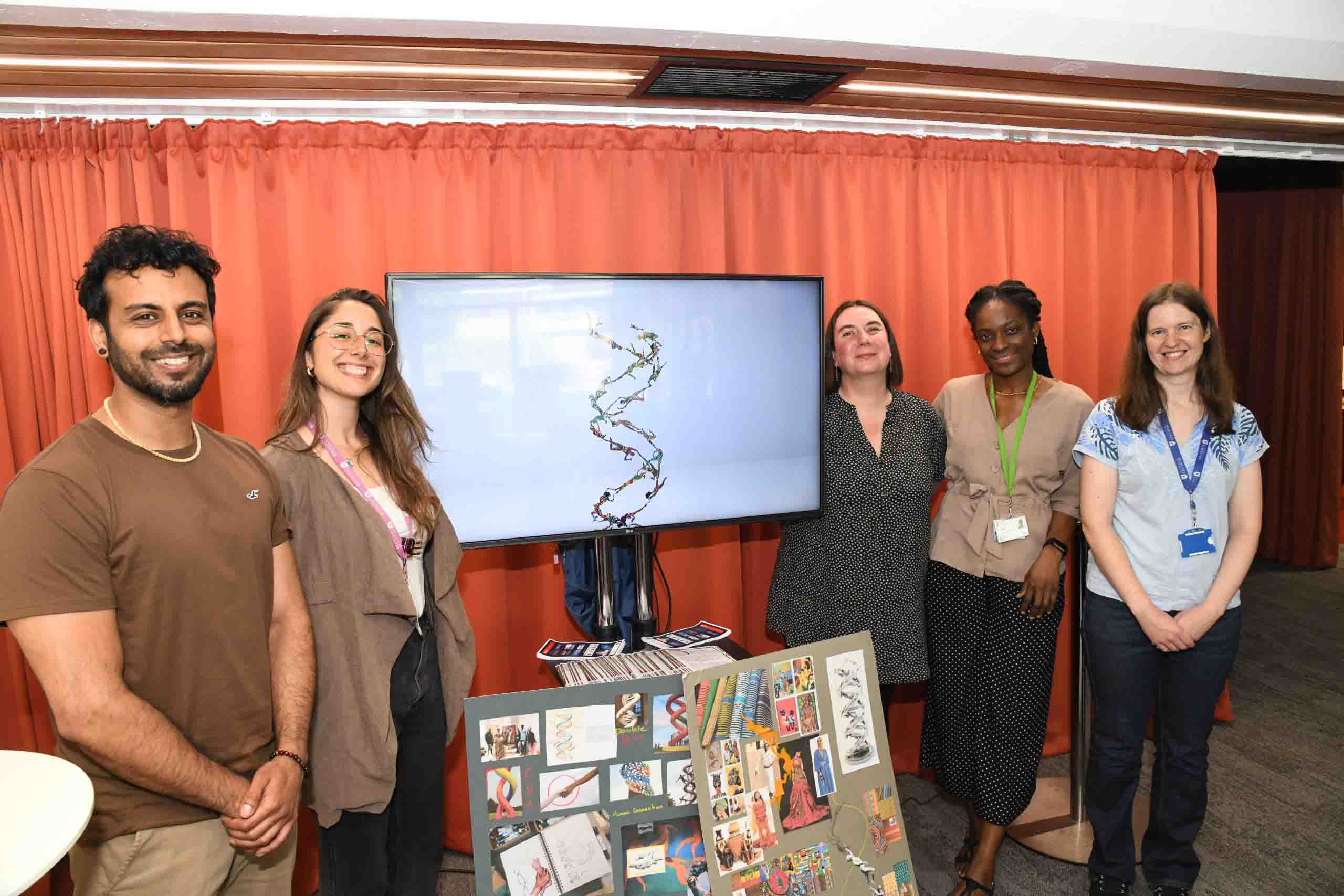 An artist and four academics smiling next to their art installations about genomics.