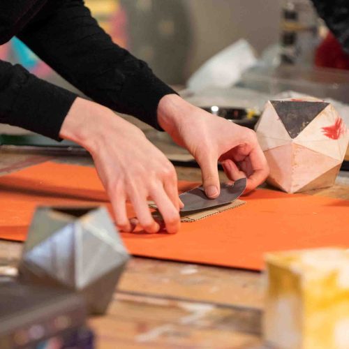 Two hand pressing paper together while surrounded by craft tools.