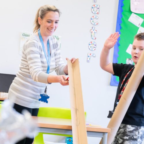 A women teacher and a child in a classroom creating with giant tubes.