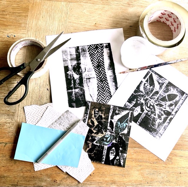 A scatter of printed papers laying on a window table with paints, pens, scissors and tapes.