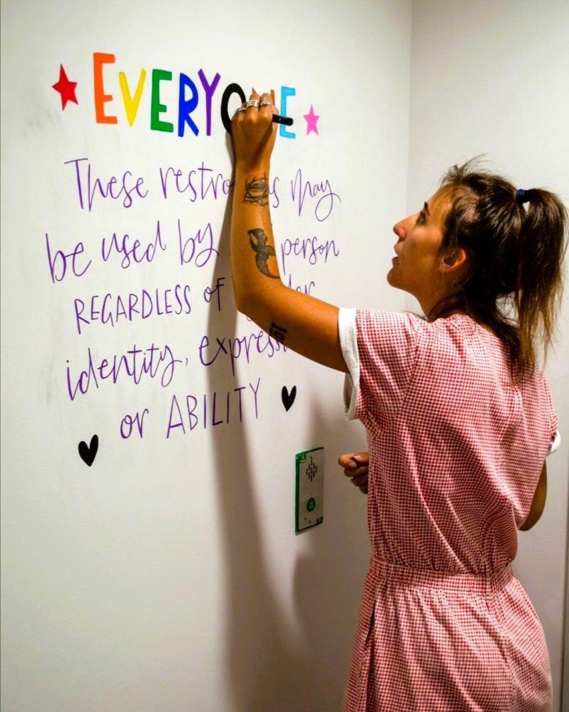 A women drawing on a wall in modern calligraphy style.