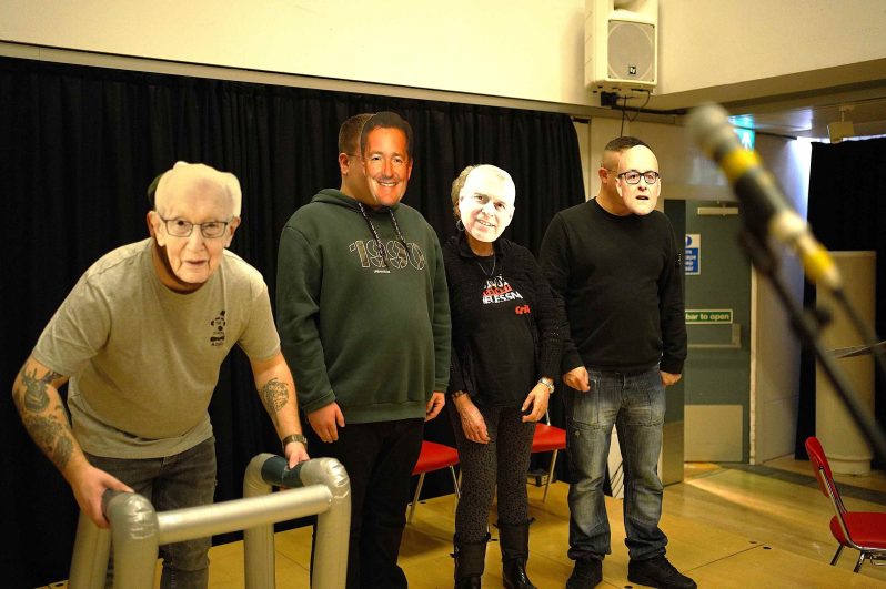 Four people with paper masks on stood in a line.