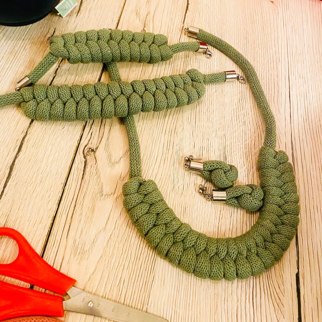 Green macramé necklaces sitting on a wooden table.