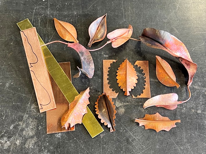 An assortment of copper sheets and copper leaves laid out on a table.