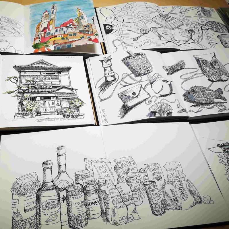 A range of sketchbooks laid out showing different pen drawings.