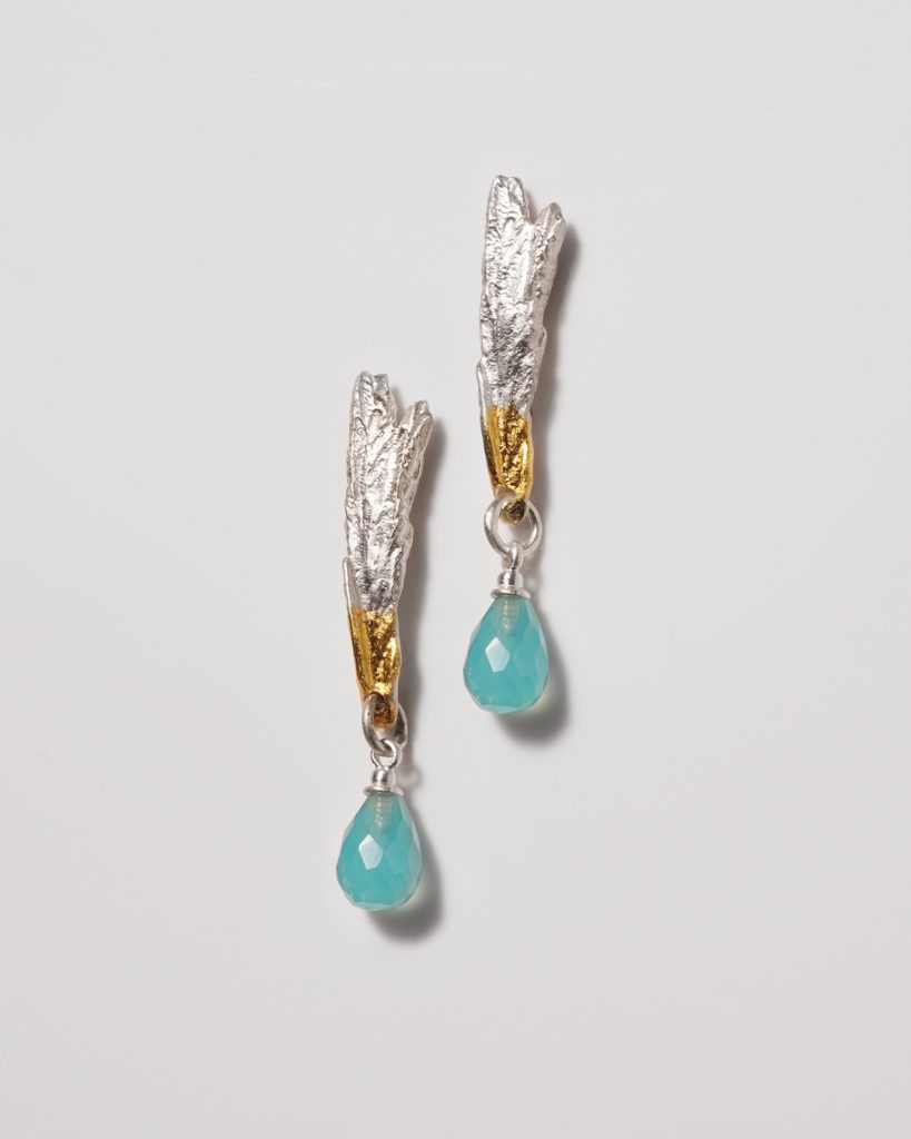 Silver and copper long textured earrings with a light blue stone on the bottom.