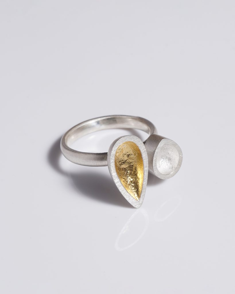 A silver ring with a tear shaped yellow stone and a clear stone.