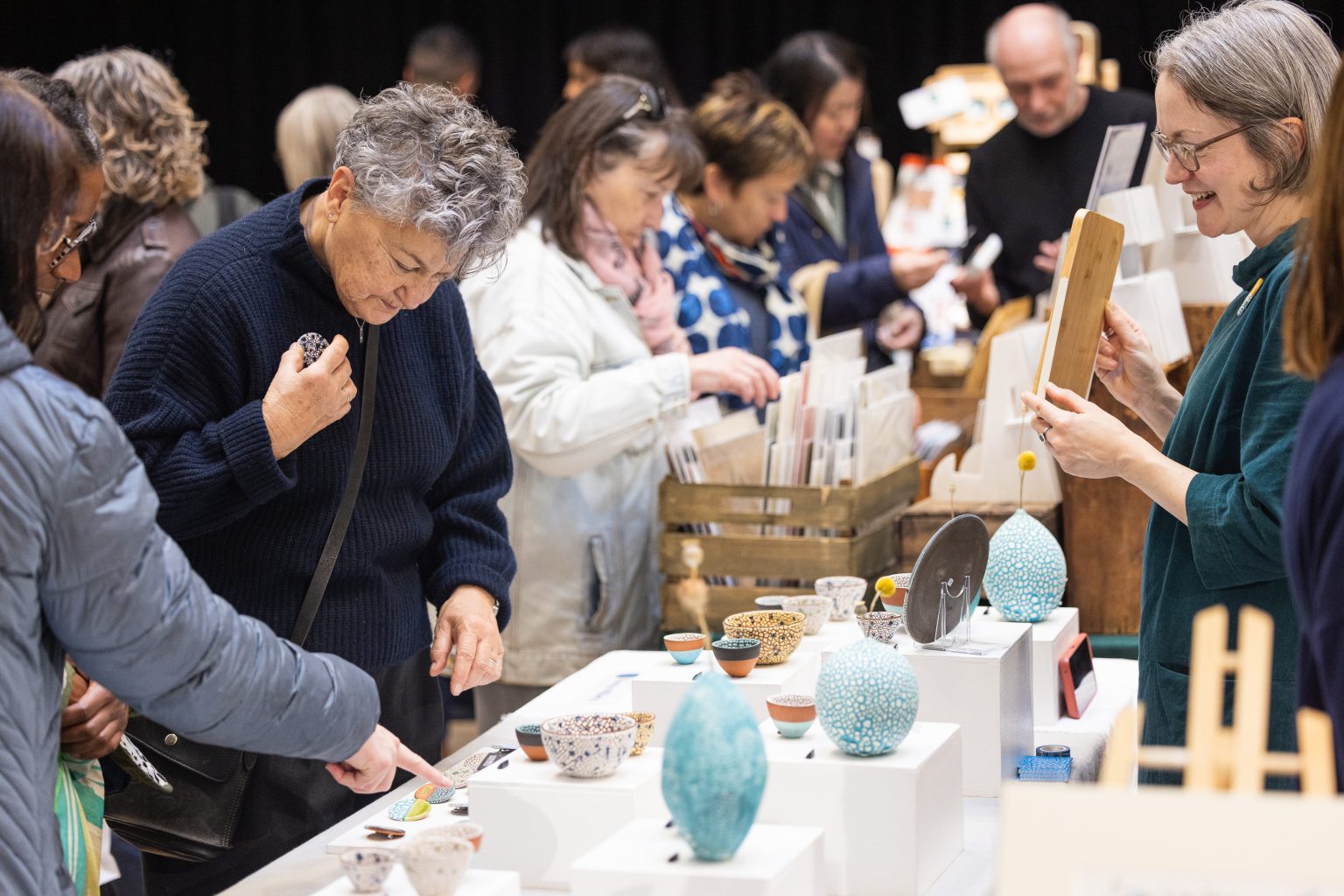 A group of people looking at a stall holding colourful ceramics.
