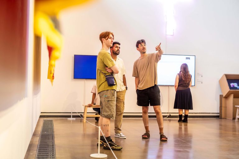 Three young men in a gallery exploring the art.