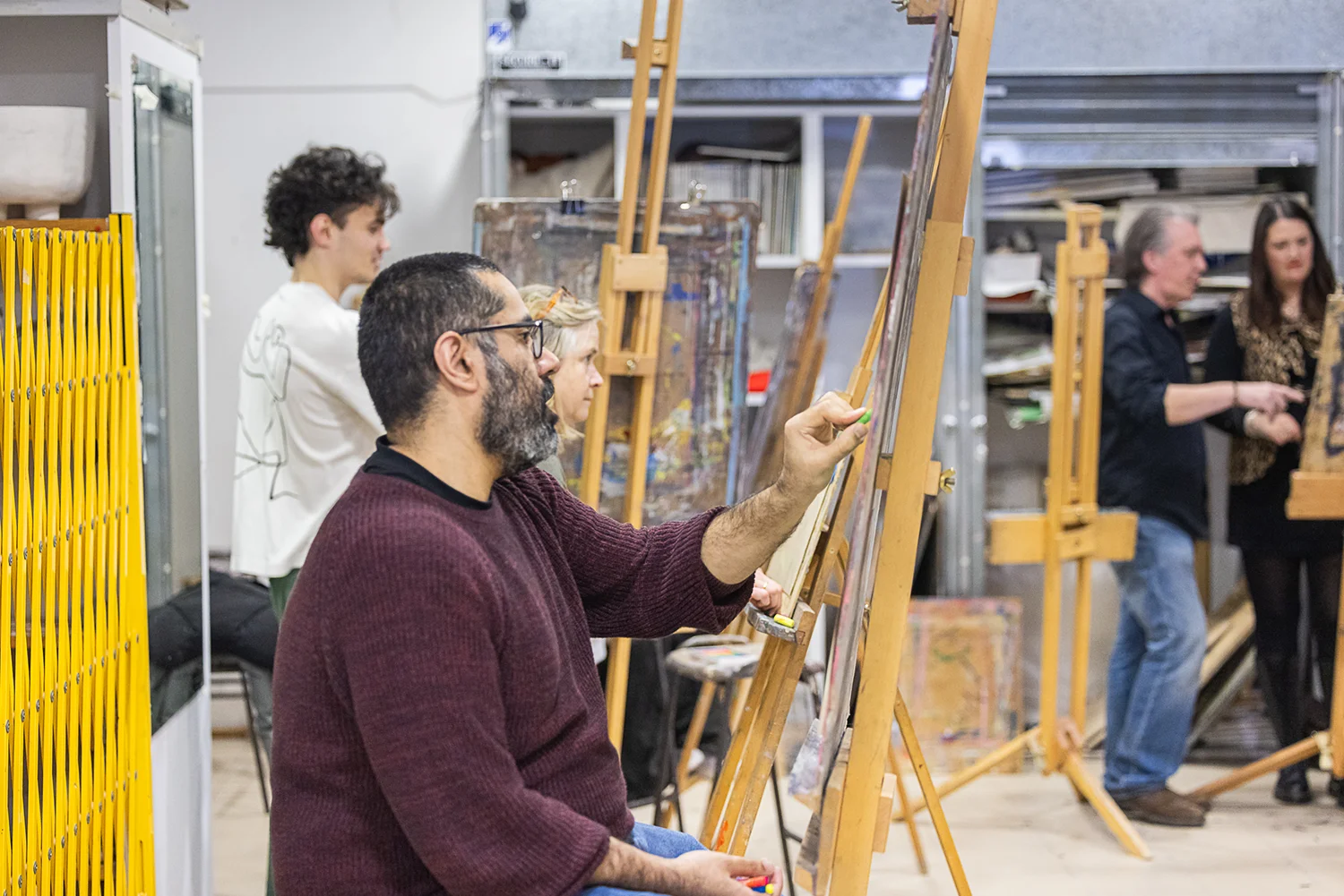 Students are shown drawing on easels in an art studio during a Life Drawing class.