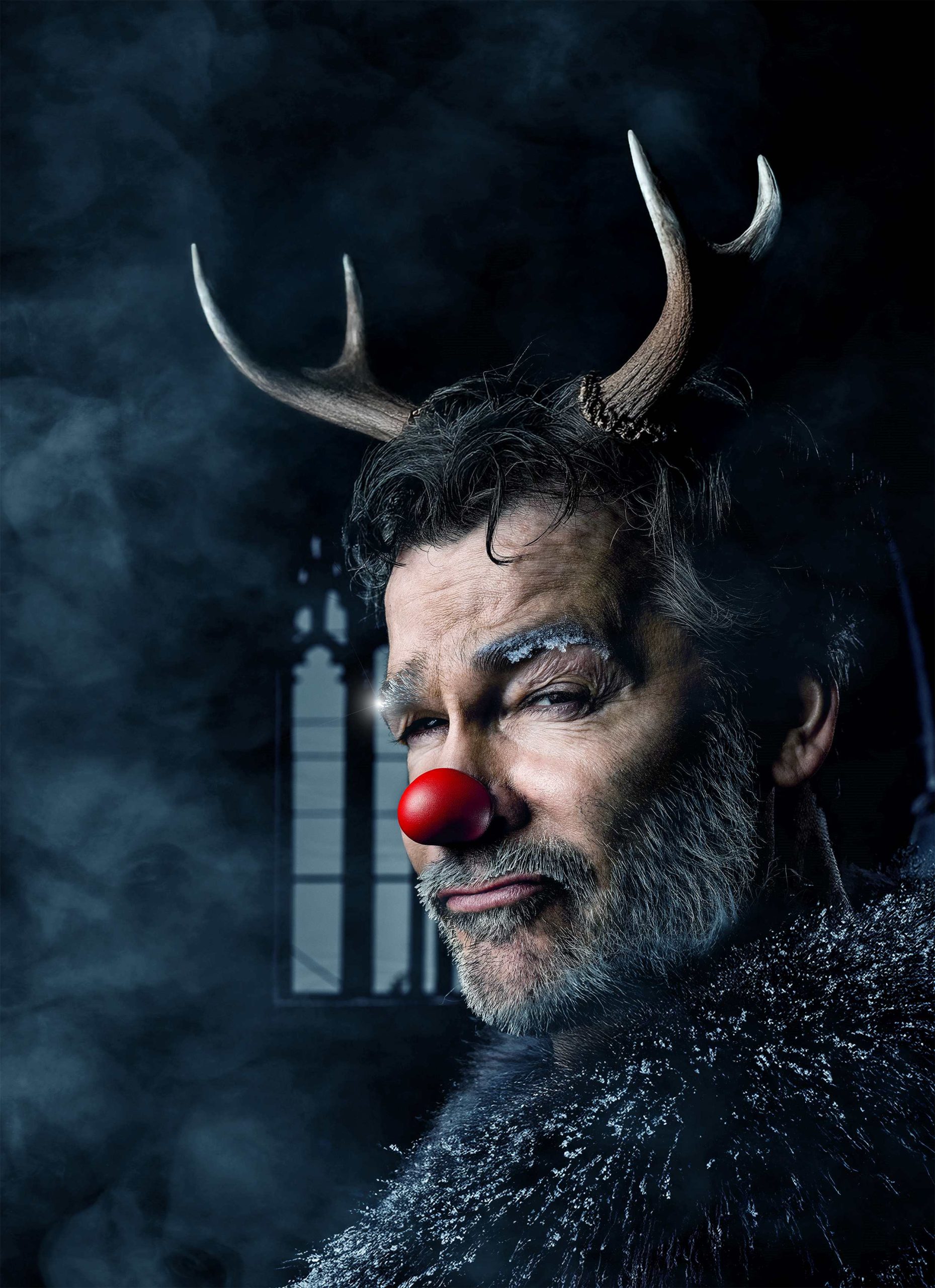 A man is shown in dark setting smokey dressed as a reindeer with antlers and a red nose with frost on his eyebrows.