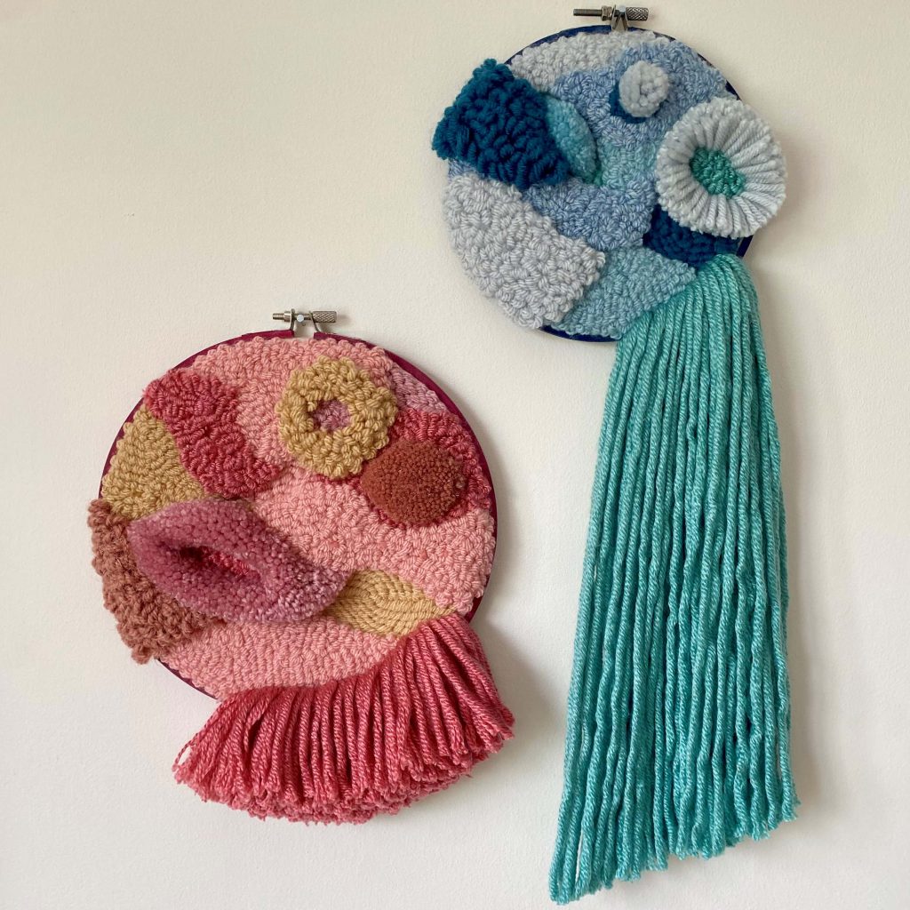 Two hoops filled with different textures of punch needle, one blue and one pink.