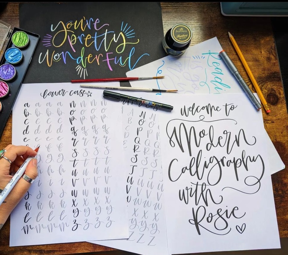 Sheets of paper with modern calligraphy practices written on them.