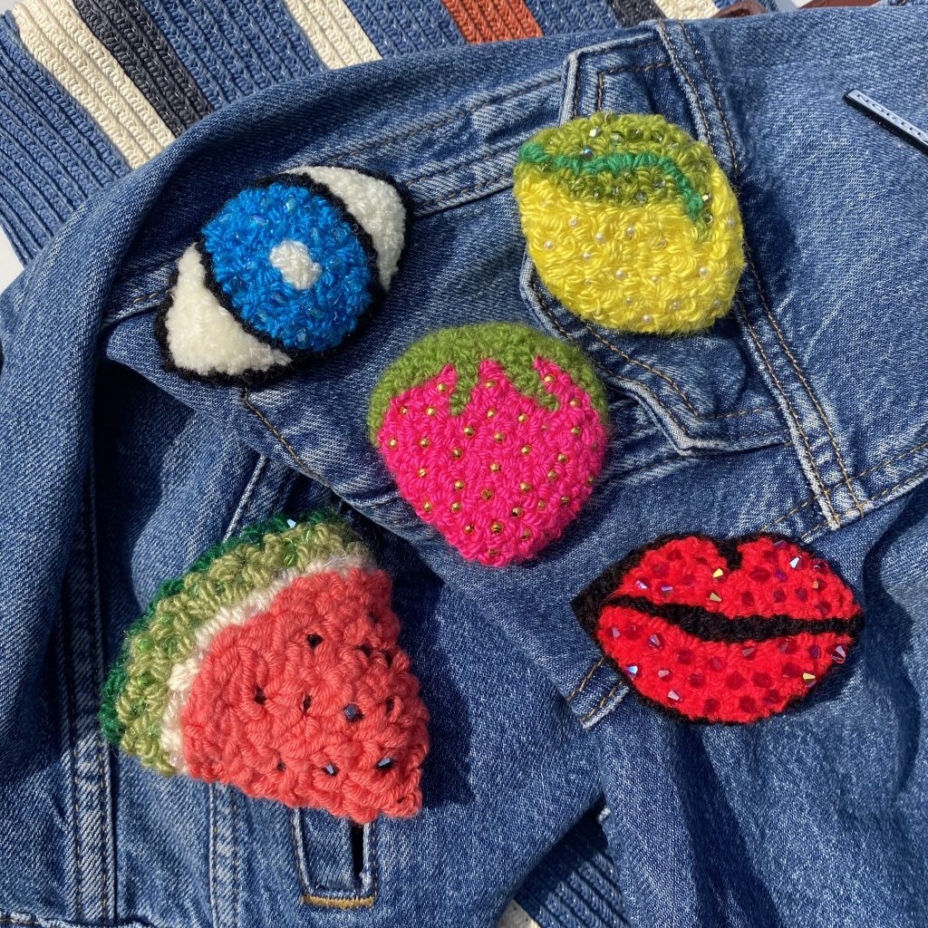 A range of fibre badges including a watermelon, lips, and an eye.