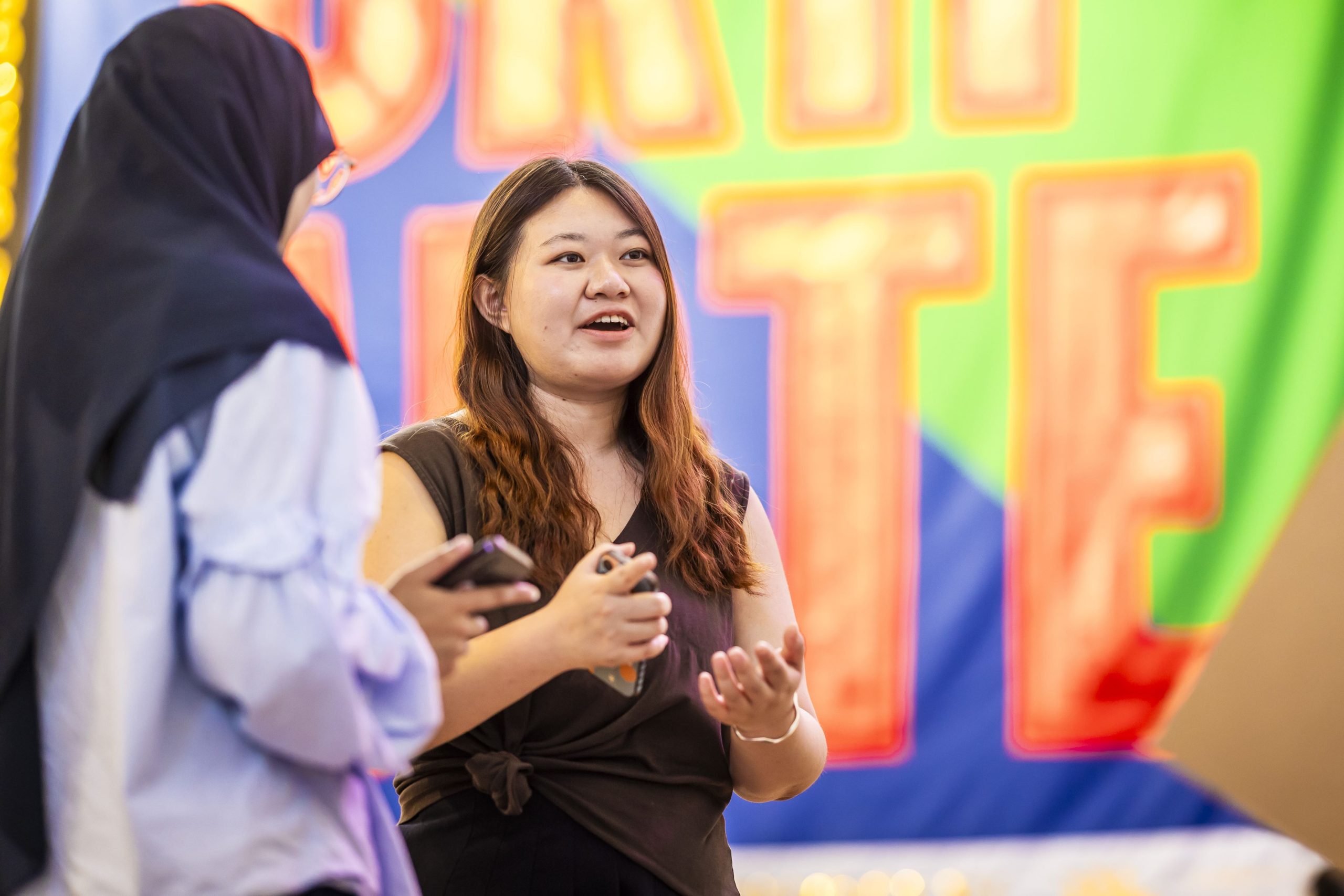 Two women talking to each other in an art gallery.