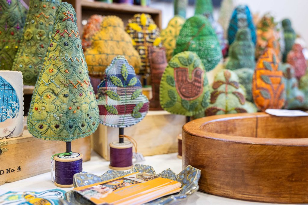 A scattering of mini holiday trees made out of textiles on a table.