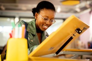 A woman smiling down while she draws on an easel.