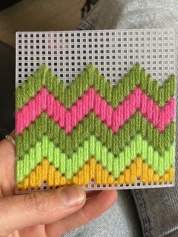 An plastic embroidery square filled with colourful zig-zags made of thread.
