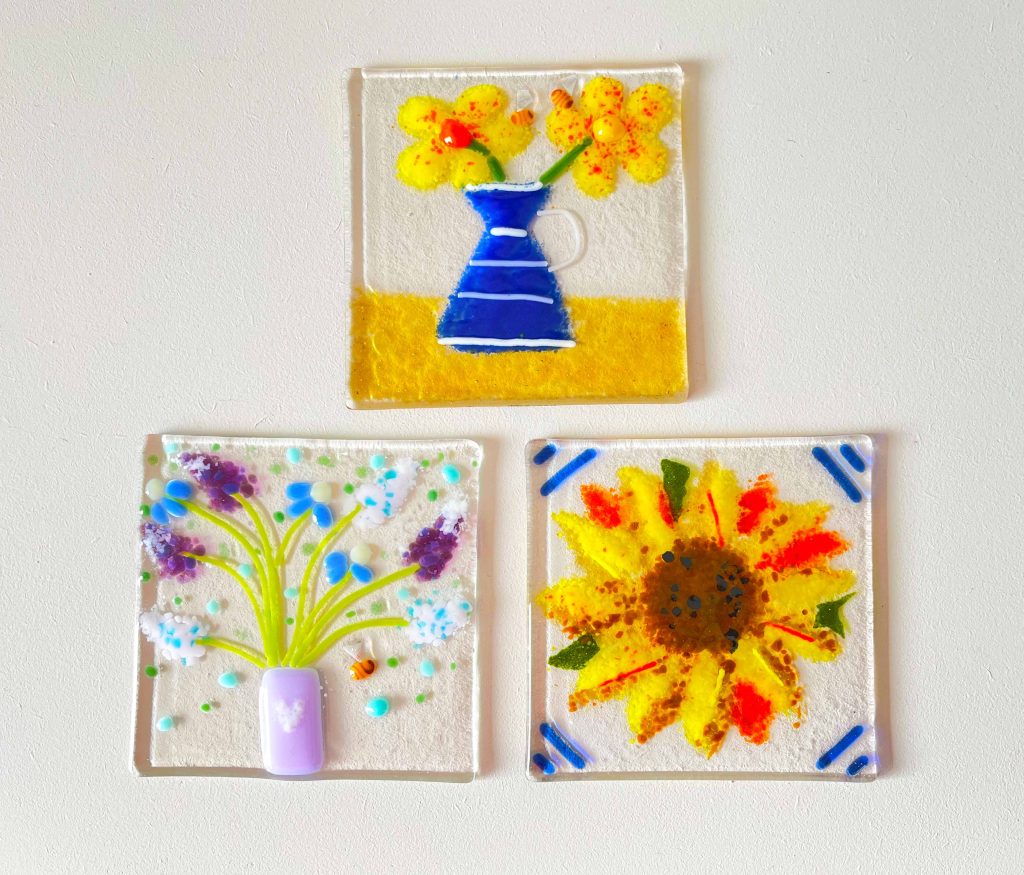 Three pieces of square glass with images of a two flower pots and a sunflower in each.