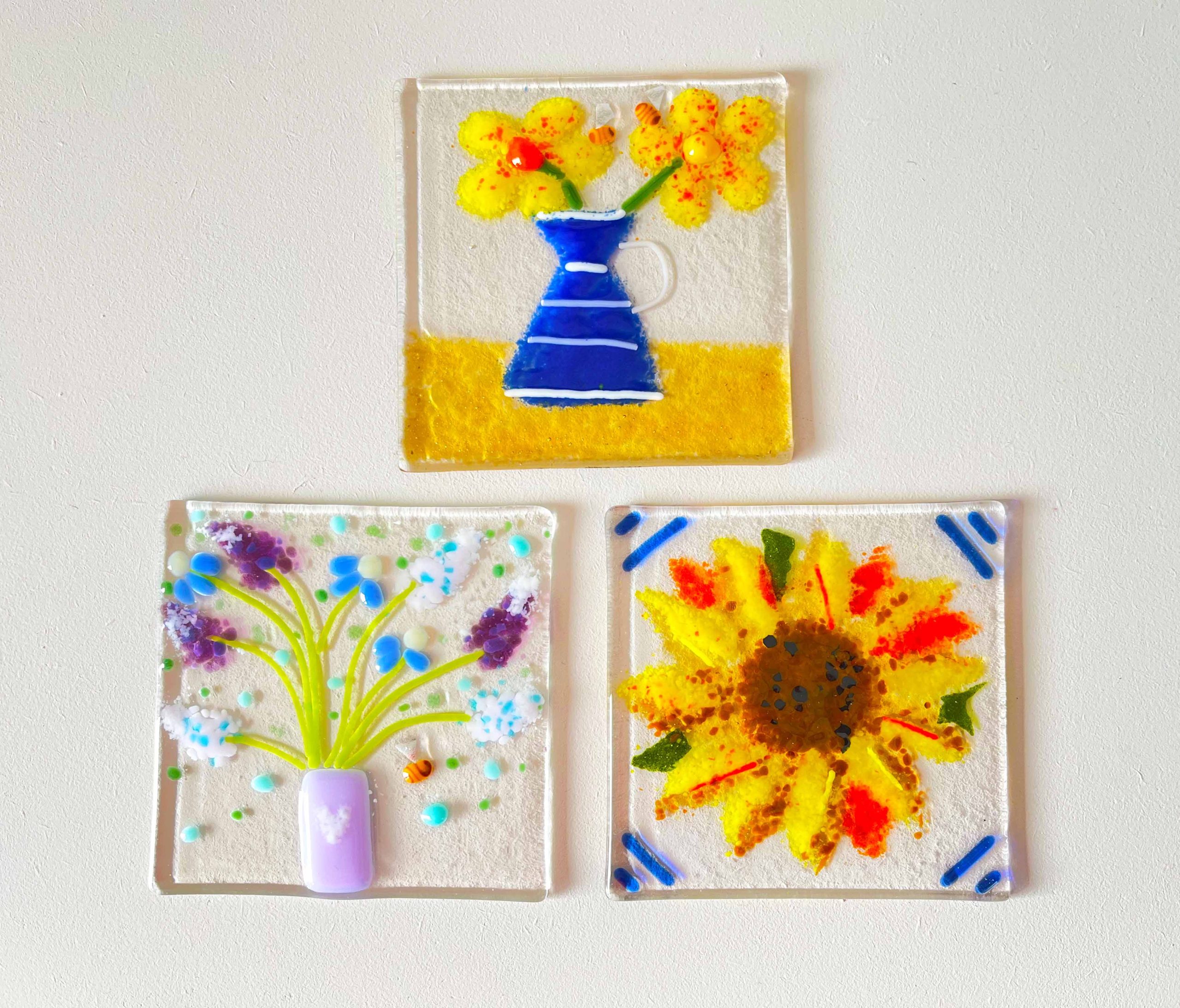 Three pieces of square glass with images of a two flower pots and a sunflower in each.