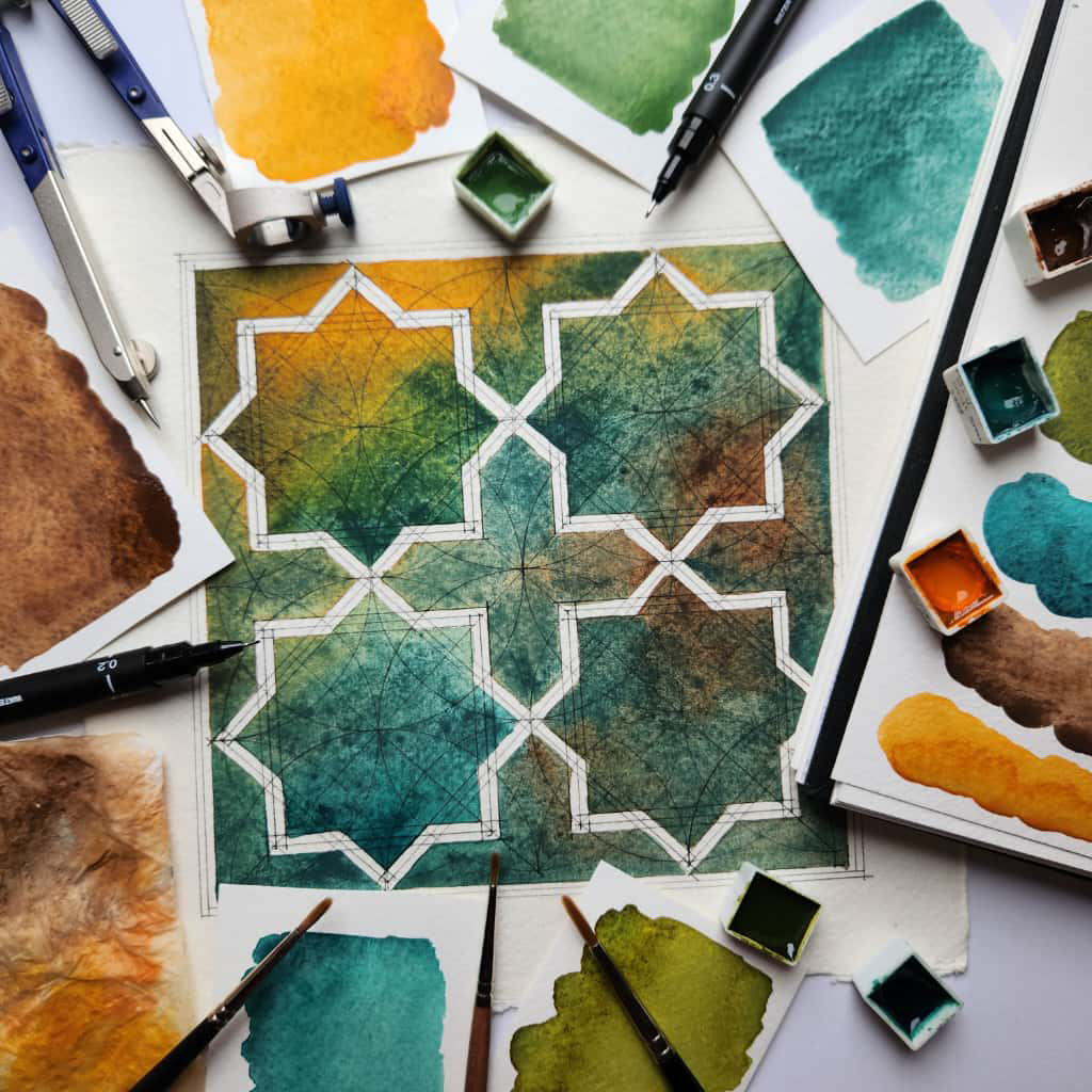 An eight fold Iranian star painted with watercolours, surrounded by the materials.