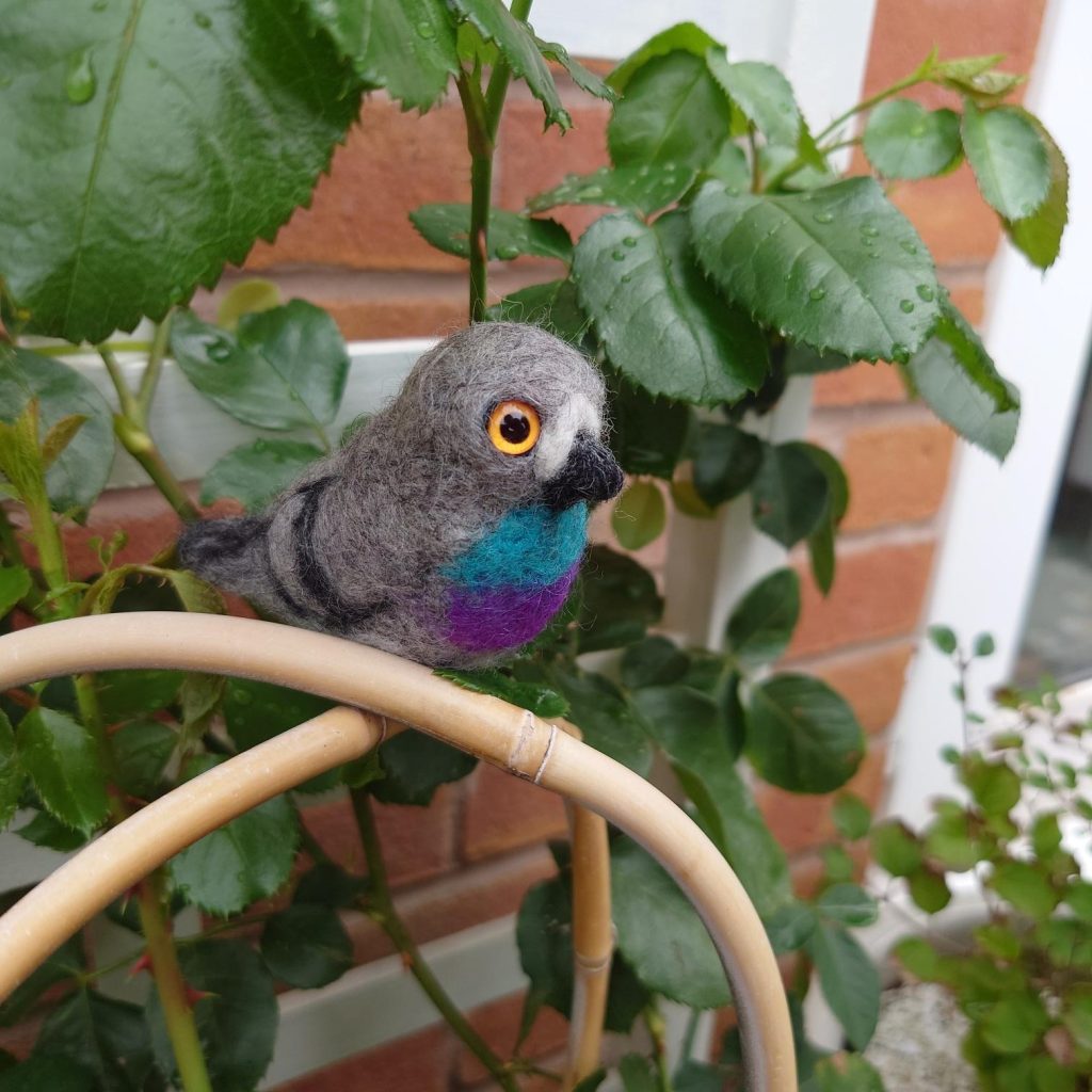 A felted pigeon sat among branches and leaves.