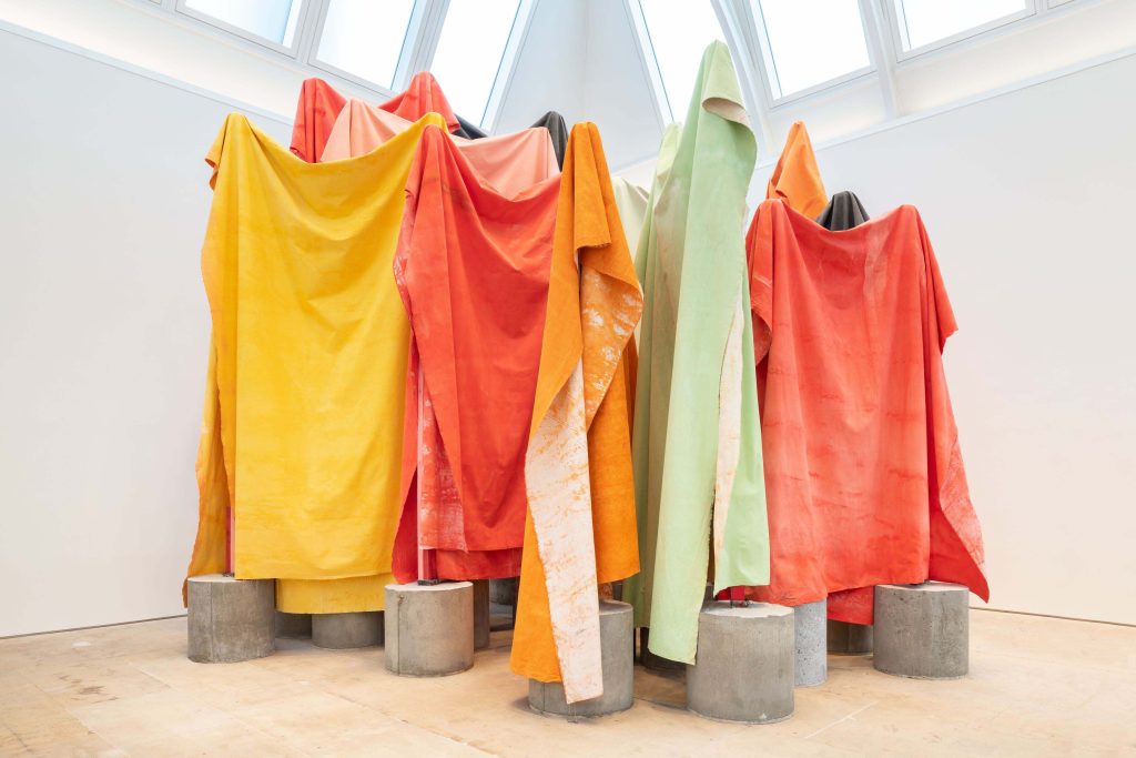 Colourful fabric draped over large stone structures in a white room.