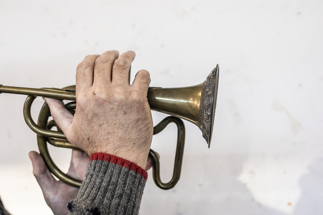 A hand holding and playing a brass instrument.